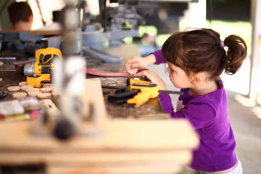 girl sanding wood discs for DIY Family Calendar Board