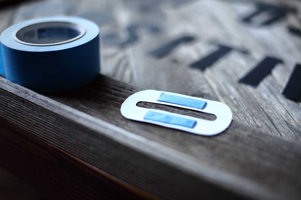 taping letter on the DIY Reclaimed Wood Frame Sign