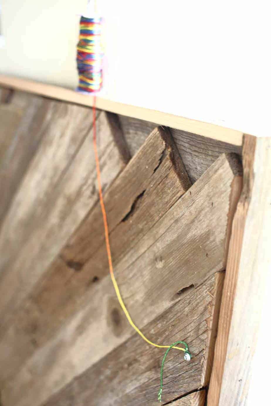 attaching string to hang the DIY Reclaimed Wood Frame Sign