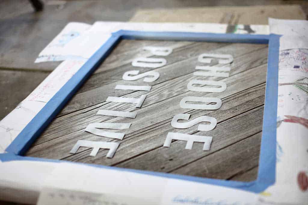spray paining the letter for the DIY Reclaimed Wood Frame Sign