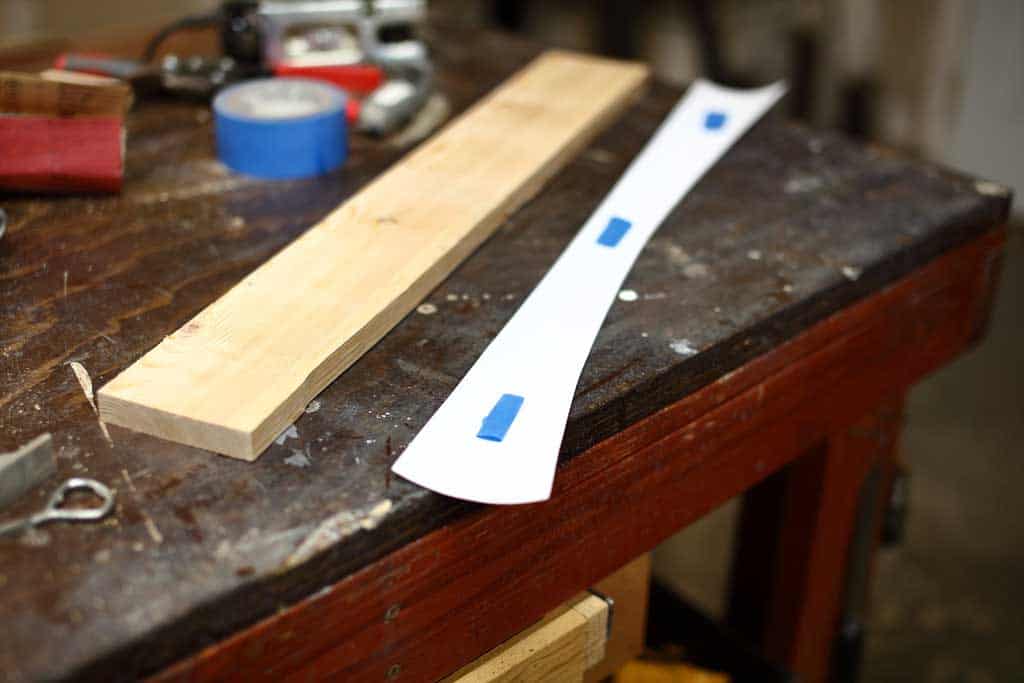 taping the template over the board for DIY Curved Shelf