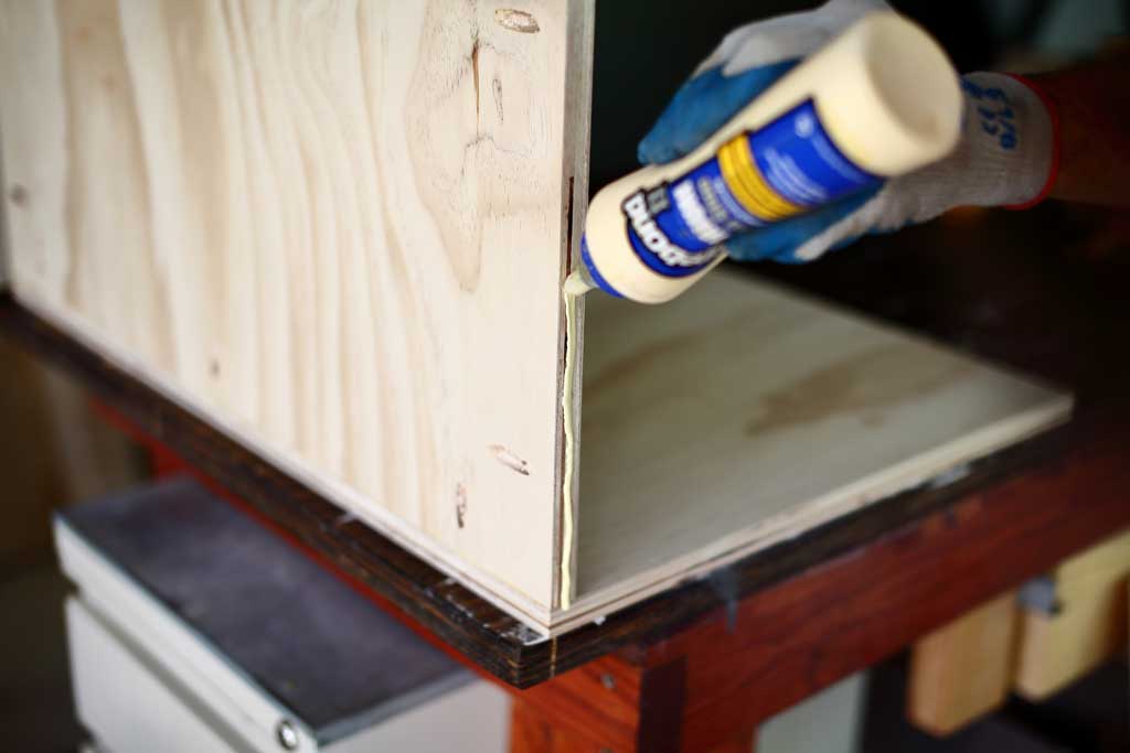 applying wood glue to the side of the cabinet