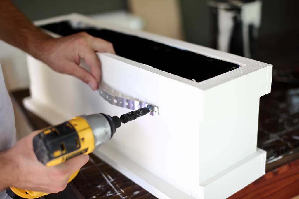 attaching plumbers strap to the planter box