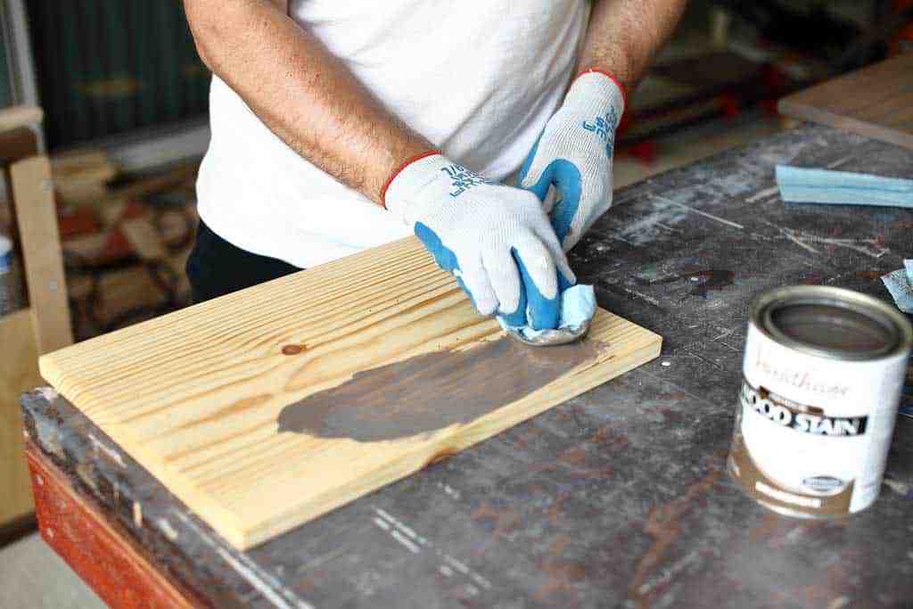 applying stain on the board for diy jar organizer
