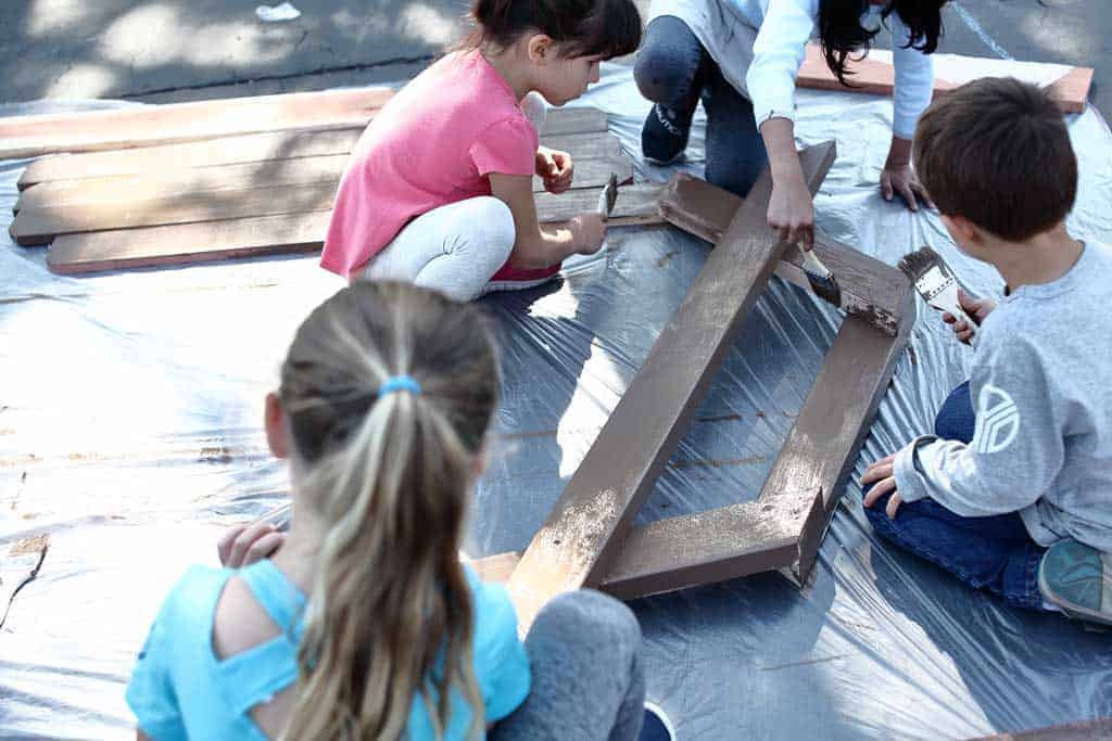 kids painting legs for the sandbox