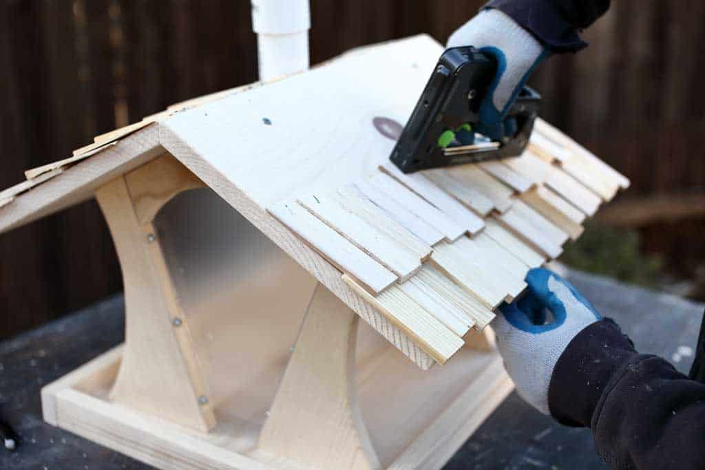 stapling wood shingles on DIY bird feeder house