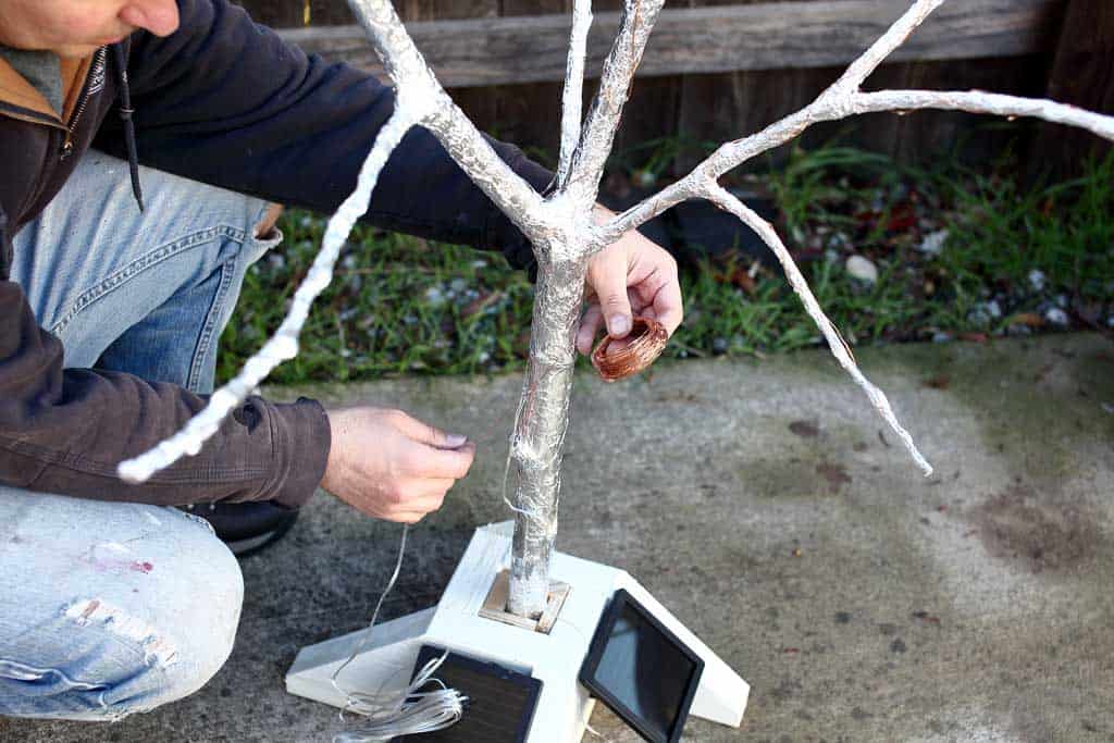 wrapping copper wire with lights around the fairy tree