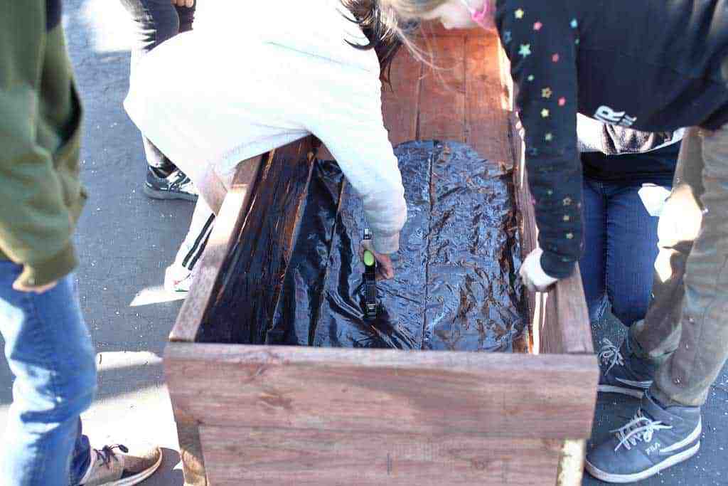 attaching plastic sheeting inside the planter box