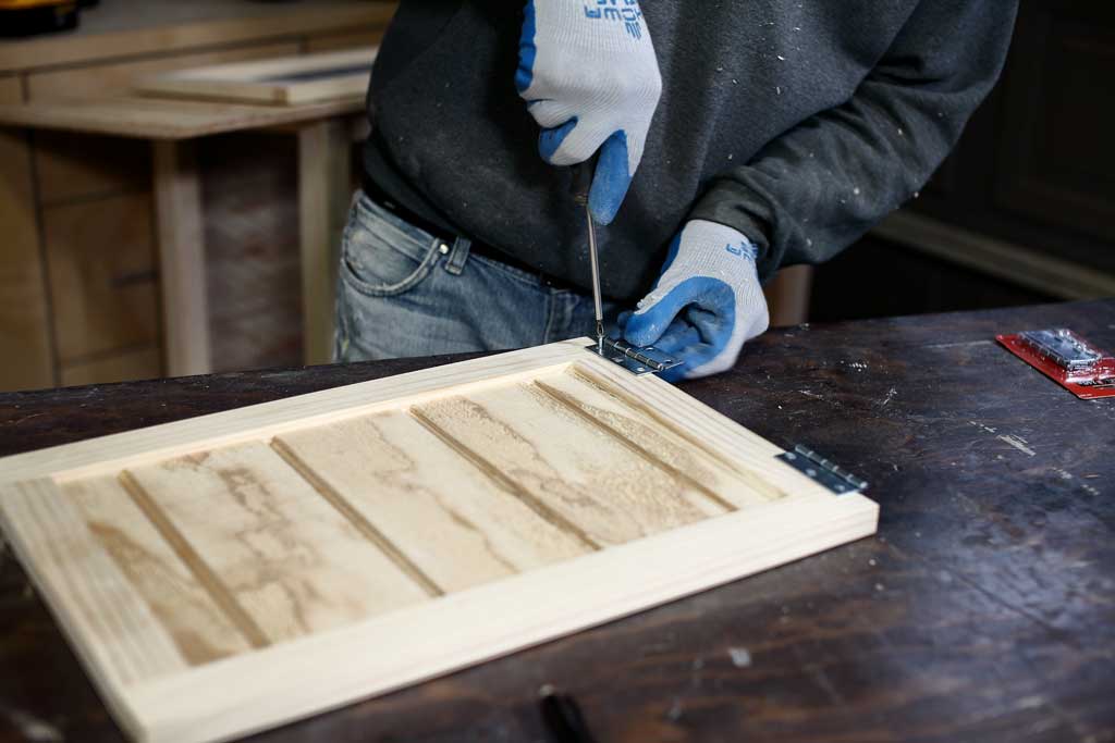 attaching hinges to the door of the DIY rabbit hutch