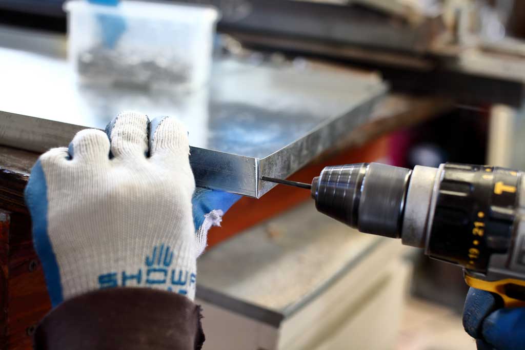 drilling hole in the litter pan of the DIY rabbit hutch