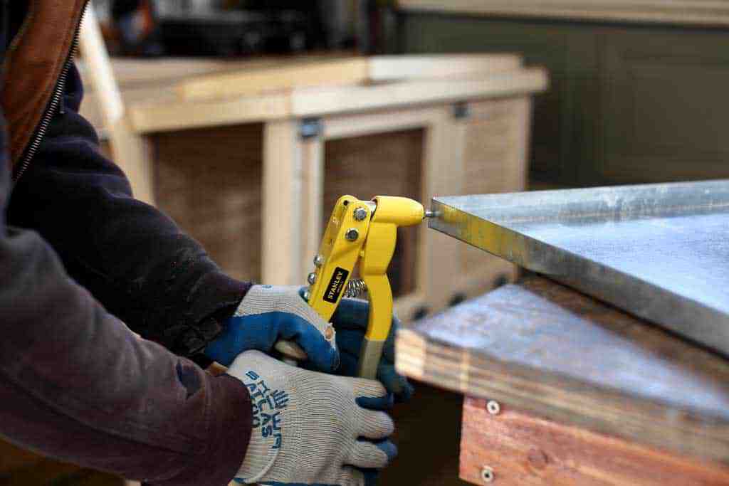 attaching pop rivets to litter pan of DIY rabbit hutch for indoor and outdoor