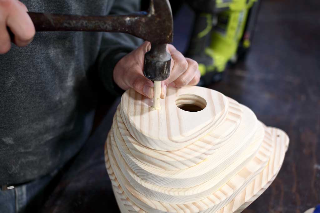 hammering dowel rod into the birdhouse